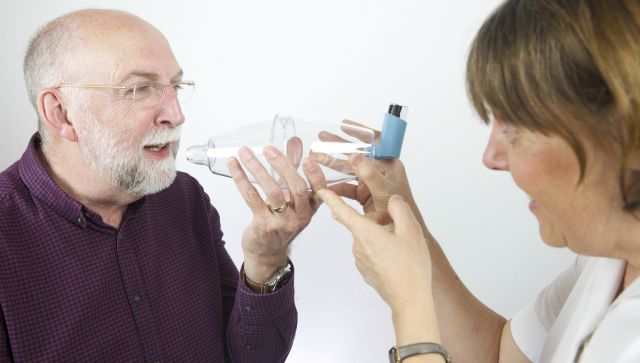 man breathing into inhaler