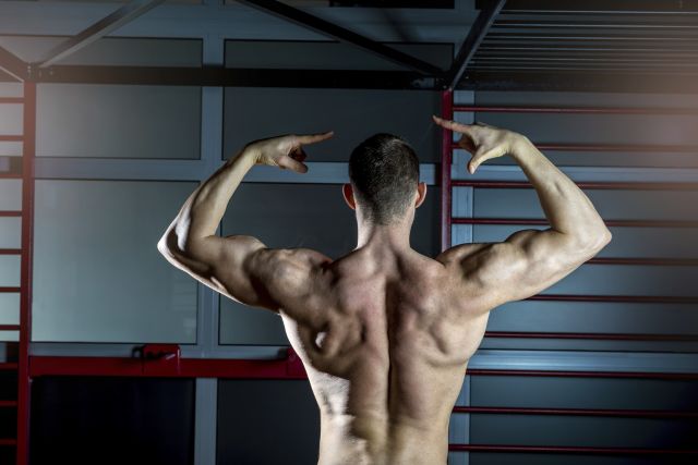 Man posing in gym showing back