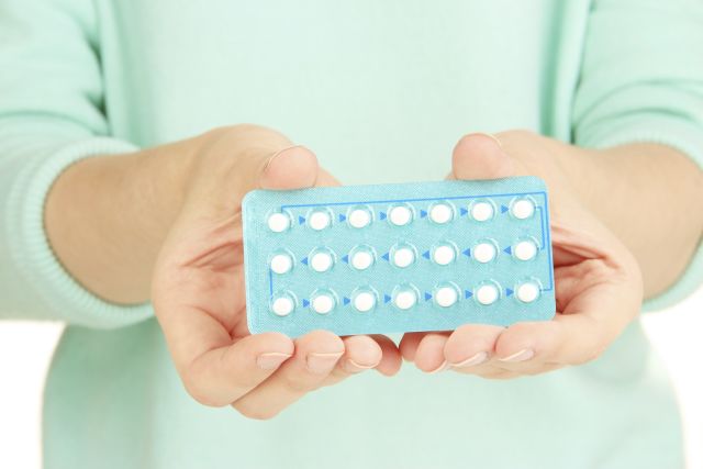 close-up of woman holding birth control pills