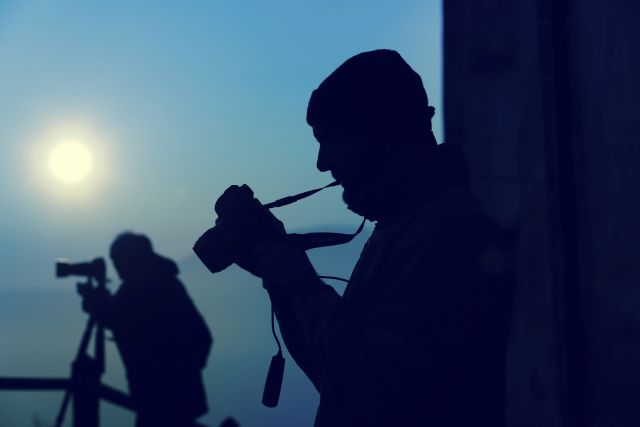 Silhouette of photographers taking photos of an amazing full moon at the top of a hill. Amateur and professional working together.