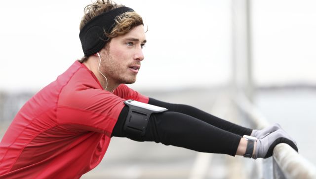 A man listens to music while stretching before going for a run. 