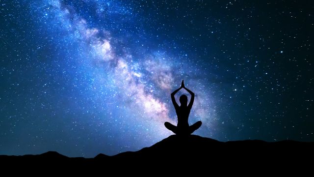 woman doing a yoga position against blue starry night, zen