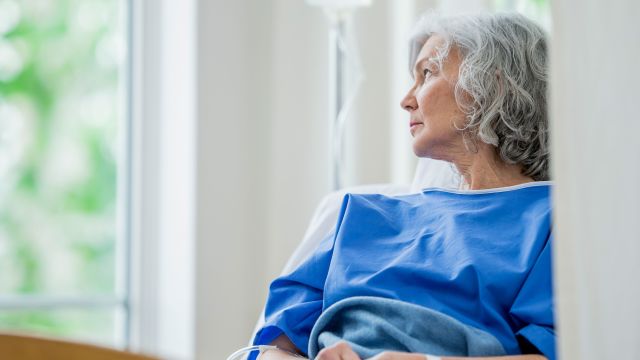 lonely senior woman staring out of hospital window