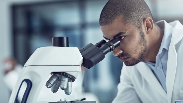 scientist looking through microscope