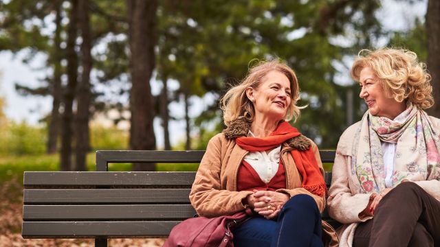 Two senior women sitting on park bench