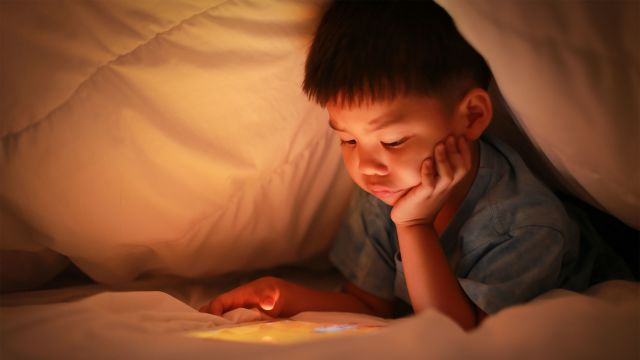 Young boy using tablet before bed