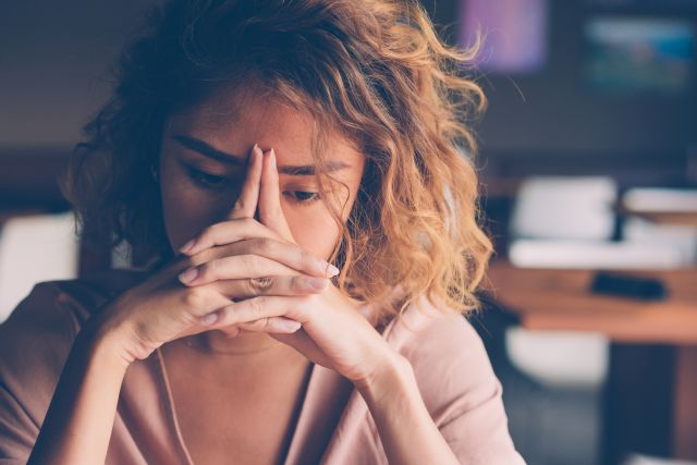 A young woman rests her her head in her hands as she struggles with fatigue from multiple sclerosis.