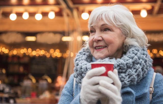 Senior woman drinking coffee outside in winter