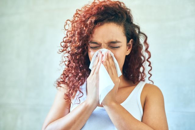 A woman with congestion blows her nose because her over-the-counter decongestant doesn’t work. 