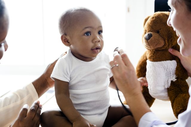 Cute baby with doctor being distracted by a bear