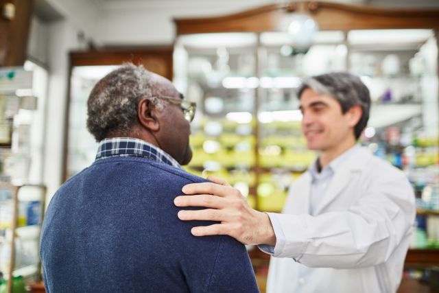 An older man consults with his pharmacist about hep C treatment. There are a number of barriers that prevent hep C patients from getting treated.
