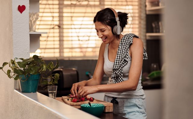 Woman wearing headphones happily cooking