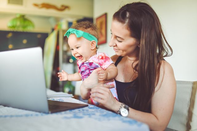 A mother and baby sit at a computer. There are a number of resources online to help families living with FOAD.