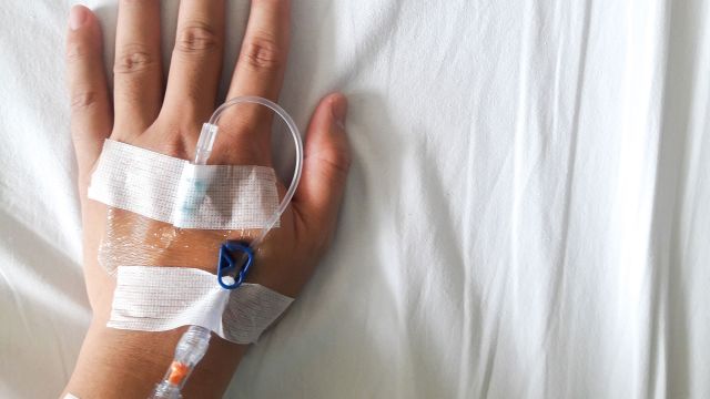 A man’s hand with an IV for infusion treatment for MS. He is receiving MS infusion medications to treat multiple sclerosis.