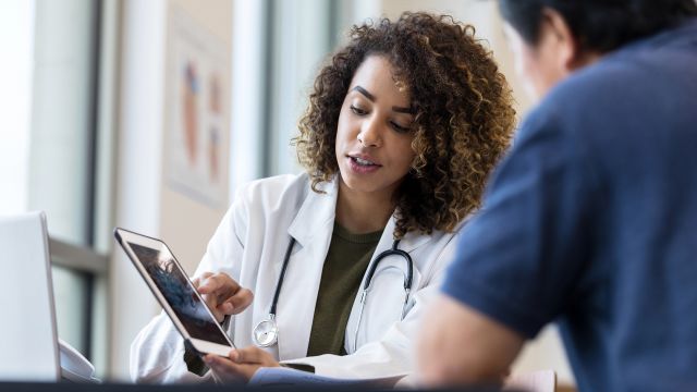 A doctor talks with her patient about his upcoming Crohn's disease surgery for inflammatory bowel disease (IBD). 