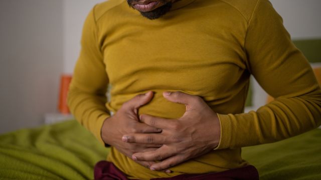 A woman searches her symptoms on a smart phone while sitting on a toilet and experiencing GI distress.