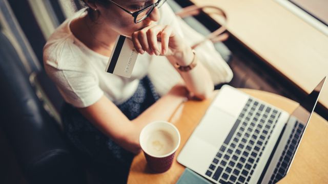 A young woman enters credit card information onto a laptop. There are resources to help people with psoriasis pay for treatment.