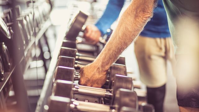 An older man lifts weights. Exercise can be beneficial to physical and mental health while undergoing treatment for advanced basal cell carcinoma.