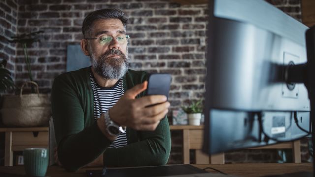 A man conducts research on skin cancer with a laptop and smartphone.