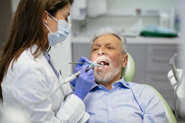 Elderly man in the dentist's chair getting his teeth cleaned.