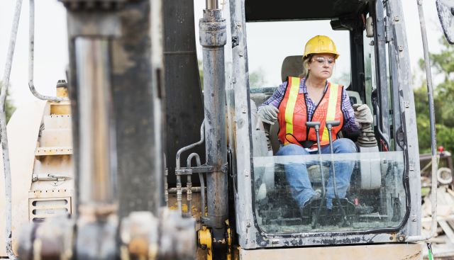 middle-aged woman in safety clothing operating bulldozer