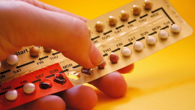 A woman's hand holding oral contraceptives in a blister pack.