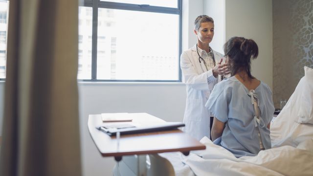 A healthcare provider examines a woman's thyroid.