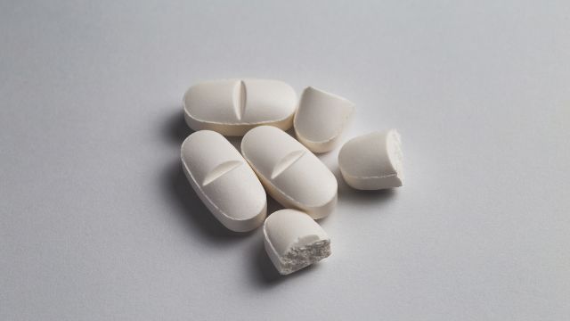 White pills set on an off-white background. Some of the pills have been cut in half.