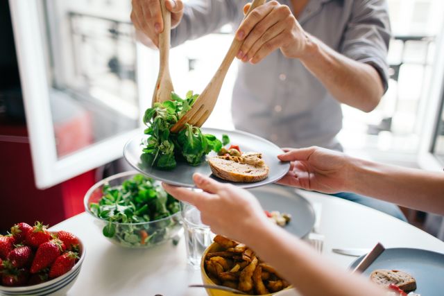 a pair of hands serve another pair of hands a healthy green salad