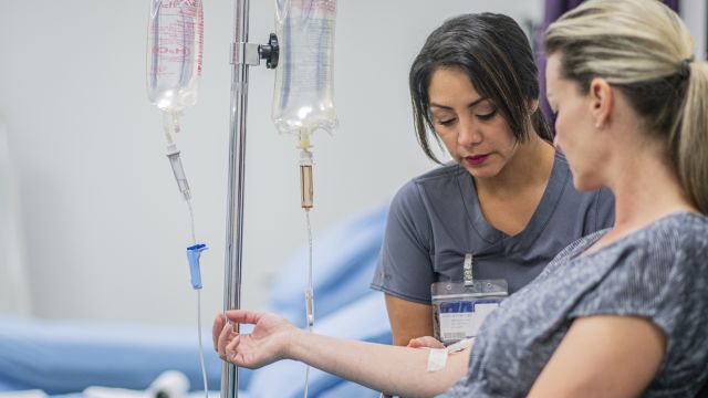 Nurse preparing an IV in the arm of a patient receiving metastatic breast cancer medication and treatment. 