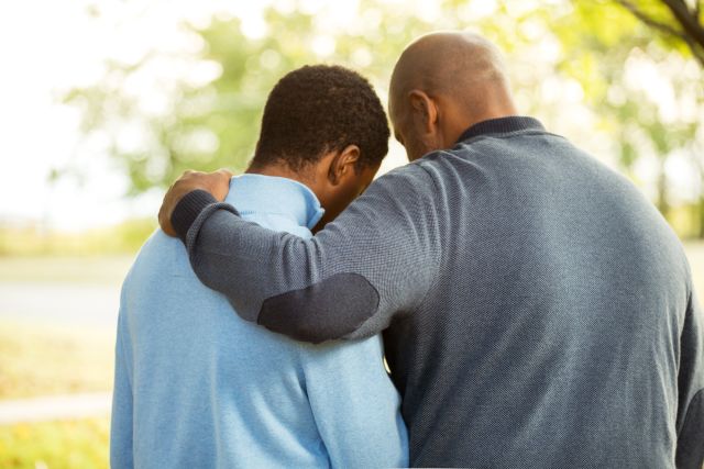 man with arm around teenage boy