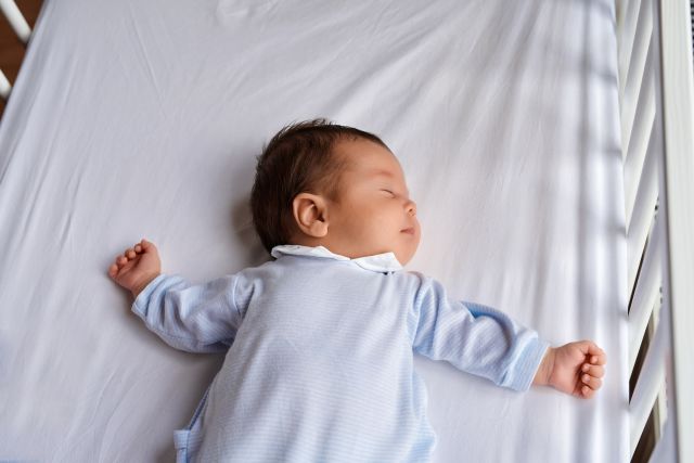 baby in crib sleeping on back with head tilted to the side