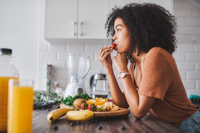 a young Black woman eats a healthy breakfast of fruit