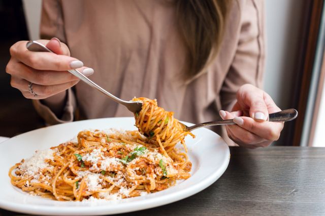 a woman dining in a healthy restaurant enjoys a plate of spaghetti