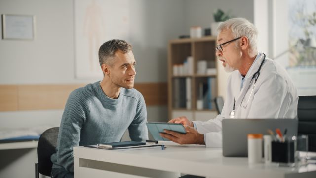 a young man speaks with an older male Asian doctor