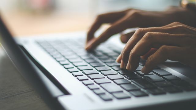 Hands type on a laptop keyboard seeking health information.