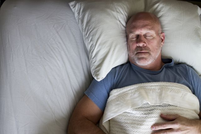 an overweight middle-aged white man sleeps in his bed