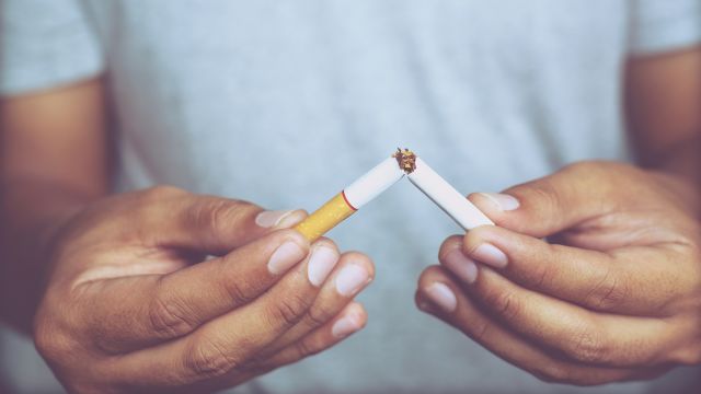 A man breaks a cigarette in half. Quitting smoking is especially important if you are living with HIV.