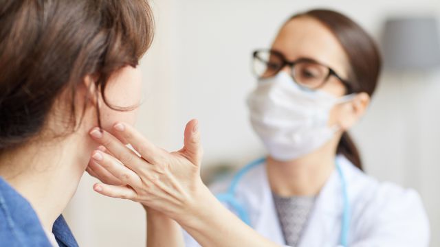 A healthcare provider examines a patient's lymph nodes during a follow-up exam for classical Hodgkin lymphoma.