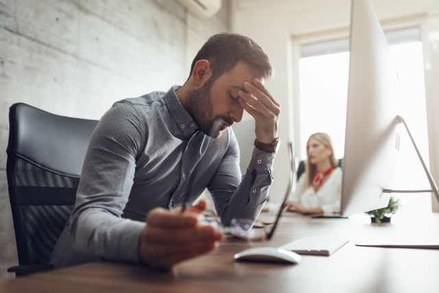 man working in office with migraine headache