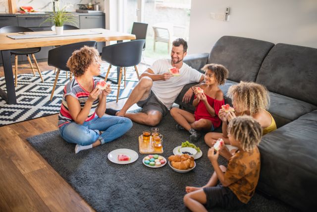 family sitting on living room floor having an indoor picnic