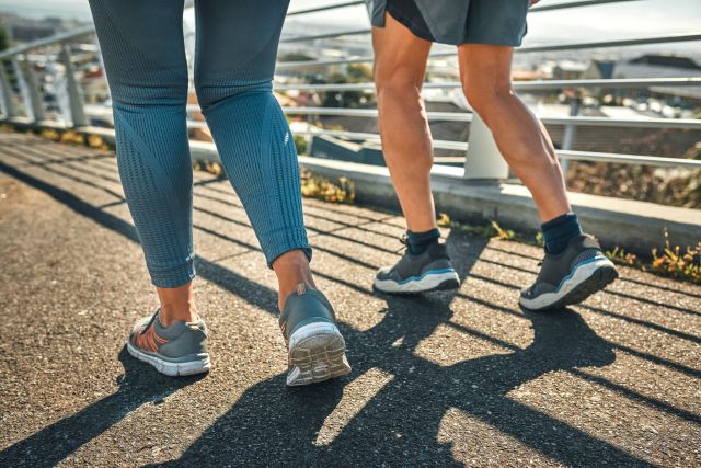 Closeup of the legs of two seniors with arthritis briskly walking across a bridge