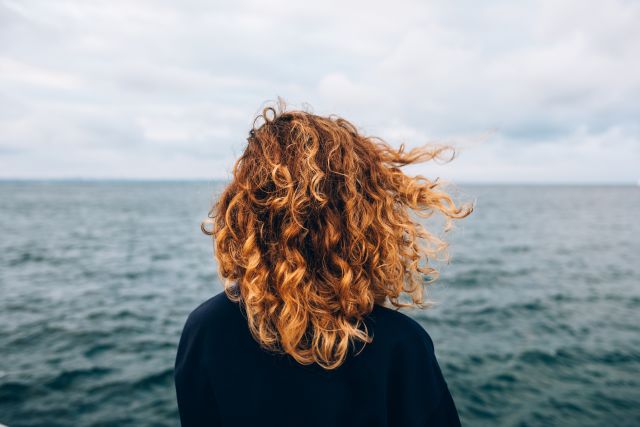 View from the back of a woman with bipolar disorder looking out at the sea