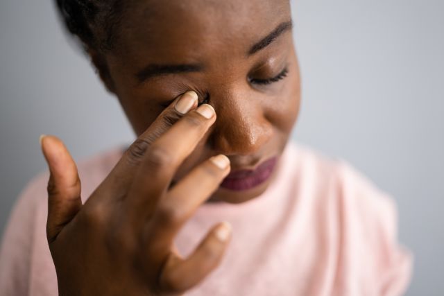 Overheard closeup view of a woman rubbing her closed eye