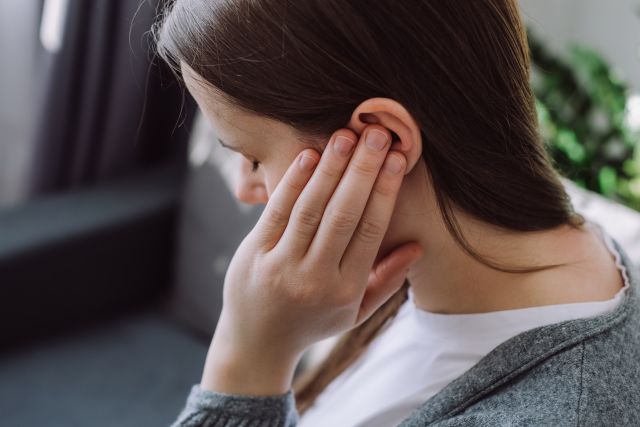 side view of woman covering ear with hand