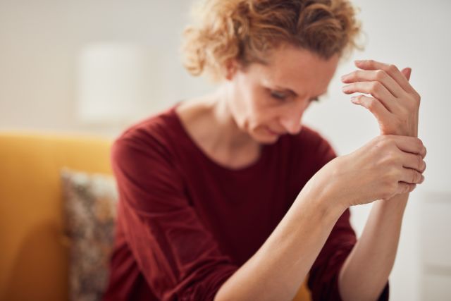 Woman with hand pain sitting on a couch at home.