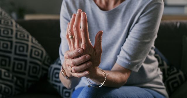 Cropped shot of an unrecognizable woman sitting alone at home and suffering from arthritis in her hands