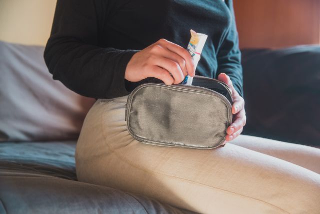 woman sitting on her couch, removing a tampon from her purse