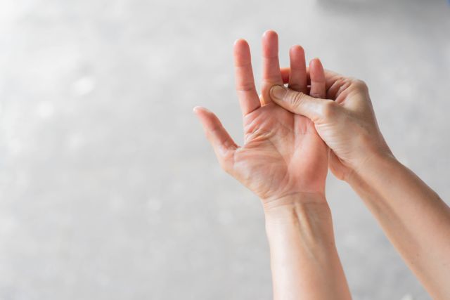 Close up senior woman massage on fingers to relief pain from rheumatoid arthritis symptoms