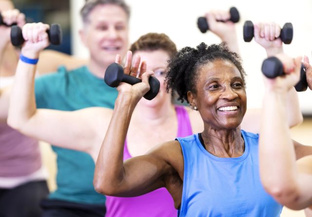 happy senior woman exercising in an indoor class with weights